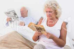 Aged couple reading a book and newspaper
