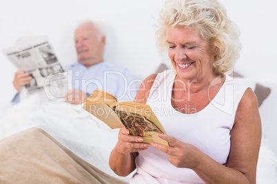 Old couple reading book and newspaper