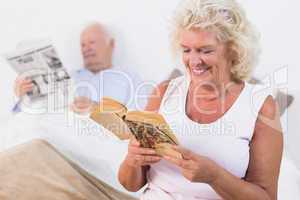 Old couple reading book and newspaper