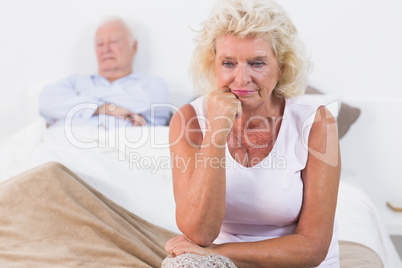 Discouraged old woman sitting on the bed