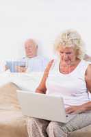 Old couple using a tablet and the laptop