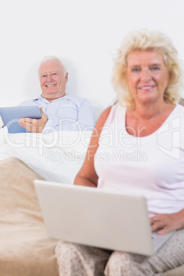 Happy old couple using a tablet and the laptop