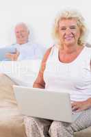 Happy aged couple using a tablet and the laptop