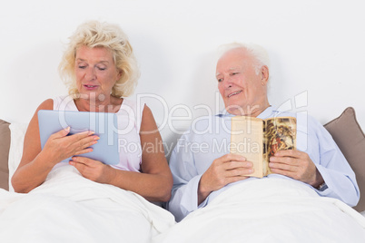 Old couple reading and using a tablet