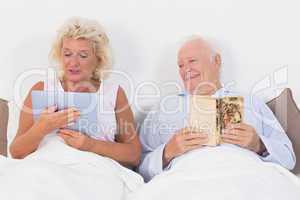 Old couple reading and using a tablet