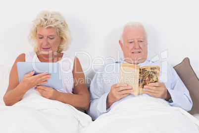 Old couple reading and using a tablet pc