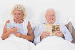 Old couple reading and using a tablet pc