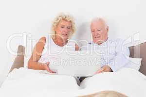 Aged couple reading or using a tablet