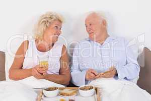 Happy aged couple eating breakfast