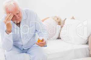 Old man looking at pills