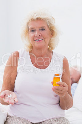 Calm aged woman with the opened pill bottle