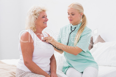 Home nurse examining an aged woman