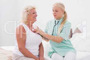 Home nurse examining an aged woman