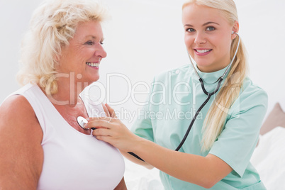 Home nurse examining a smiling aged woman