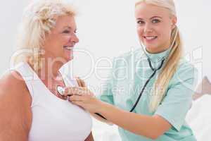 Home nurse examining a smiling aged woman