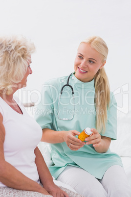 Home nurse showing a pill bottle