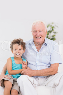 Happy grandfather and grandson sitting on the sofa