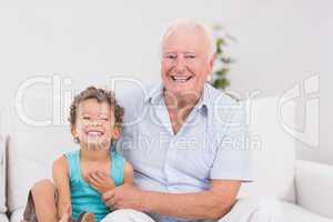 Cheerful grandfather and grandson sitting on the sofa