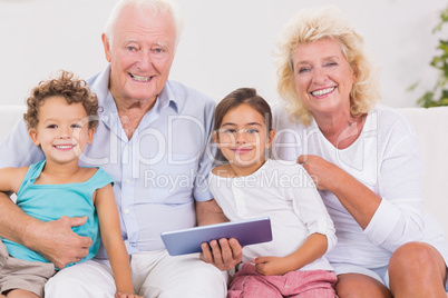 Smiling grandparents with children using a tablet pc