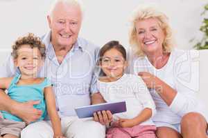 Smiling grandparents with children using a tablet pc