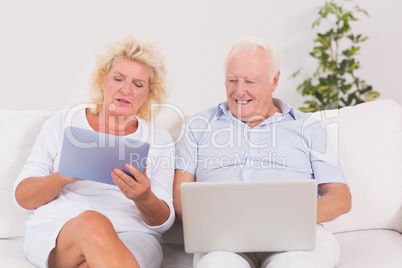 Aged couple using a laptop and the tablet