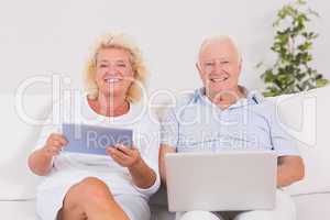 Smiling old couple using a laptop and the tablet