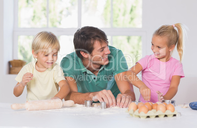 Father and his children cutting cookies out