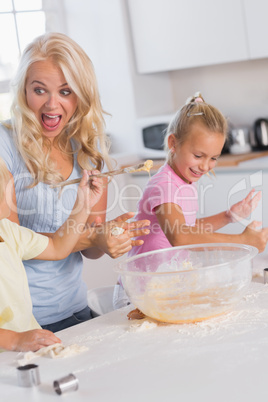 Mother making a face while her children take care of the dough