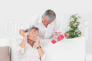 Old man hiding eyes his wife to give a gift