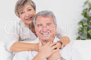 Old couple smiling at the camera and hugging