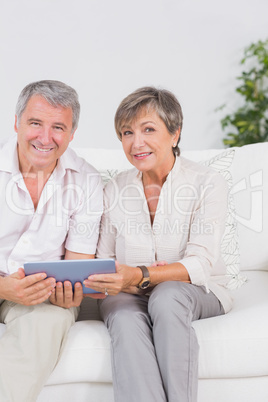 Old lovers looking camera with tablet pc