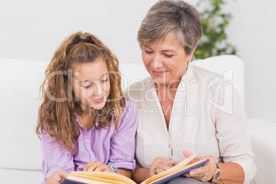 Portrait of a child and her grandmother reading a book