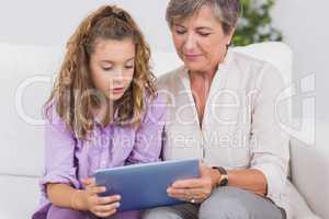 Child and her grandmother holding tablet pc