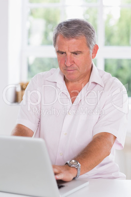 Old man using laptop seriously