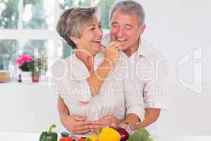 Old man tasting vegetable held by wife