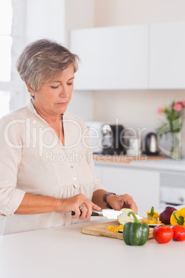 Old woman cutting vegetables on a cutting board