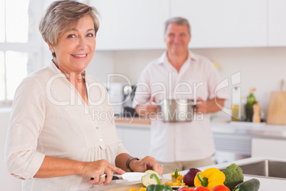 Old couple smiling preparing food