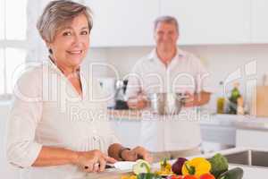 Old couple smiling preparing food