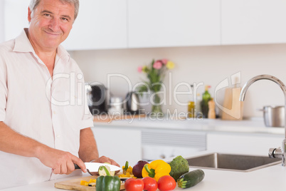 Old man smiling and preparing vegetables