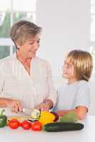 Grandmother cutting vegetables looking at grandson