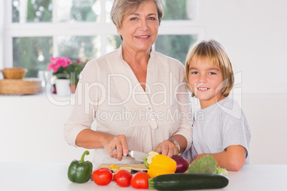 Grandmother cutting vegetables with her grandson