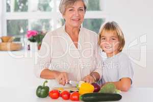 Grandmother cutting vegetables with her grandson