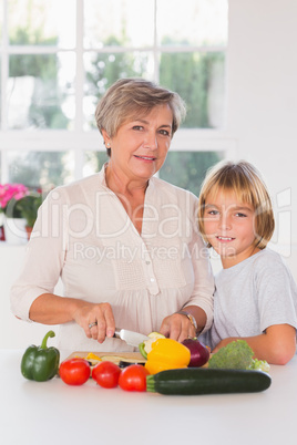 Granny cutting vegetables with her grandson