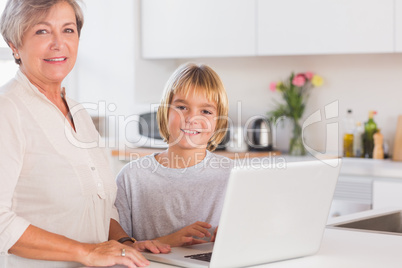 Grandmother and child looking at the camera with a laptop