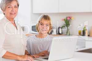 Grandmother and child looking at the camera with a laptop