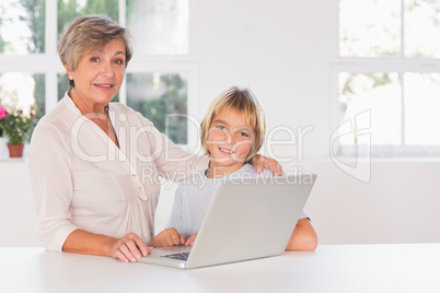Granny and child looking camera with a laptop