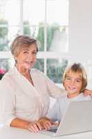 Grandmother and child looking camera with a laptop