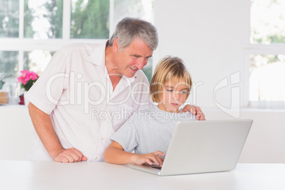 Grandfather and child looking at laptop with smile