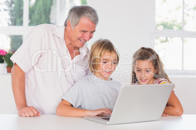 Grandfather and children looking at laptop together