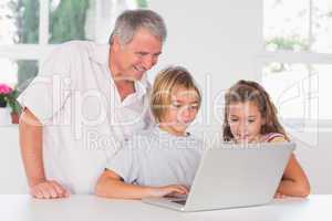 Grandfather and children looking at laptop together